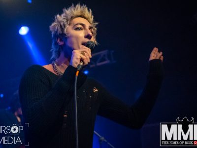 The vocalist of Palaye Royal sining into his microphone whilst holding his other hand up to the side of him.